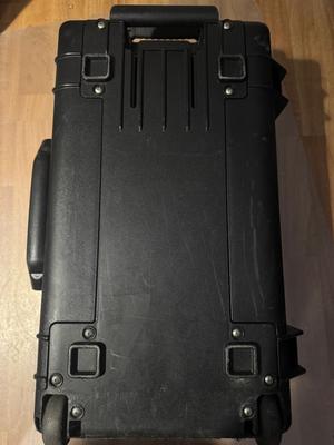 The case with the handle assembly removed from the back and placed on top of the case